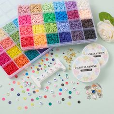 several different colors of beads in plastic trays next to a flower and brooch pins