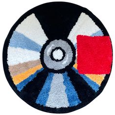 a round rug with different colors and shapes on the front, including black, white, blue, red, yellow and orange