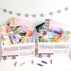 two baskets filled with school supplies sitting on top of a white table next to a string of stars