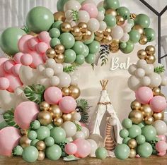 the balloon arch is decorated with pastel green, pink and gold balloons for a boho birthday party