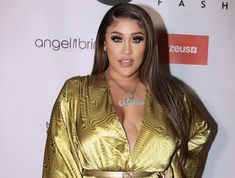 a woman in a gold robe posing for a photo on the red carpet at an event