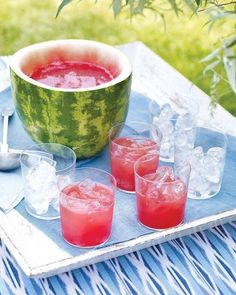 a watermelon bowl and four glasses filled with liquid