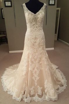 a wedding dress on display in front of a mirror with a mannequin behind it