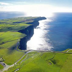 an aerial view of the ocean and land around it, with green fields on both sides