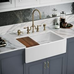 a white kitchen sink sitting under a faucet on top of a marble counter