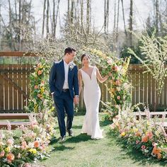 a bride and groom walking through the garden