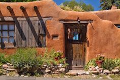 an adobe - style house with wooden shutters and windows is seen in this image