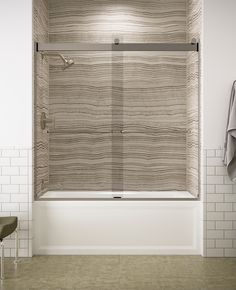 a bathroom with white tile walls and a bathtub in the center, along with two towels hanging on the wall