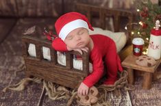 a baby sleeping in a wooden sleigh next to a christmas tree and decorations