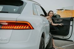 a woman sitting in the open door of a white car