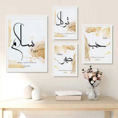 three framed art pieces hanging on the wall above a table with flowers and vases