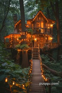 a tree house with lights on it and stairs leading up to the top floor in the woods