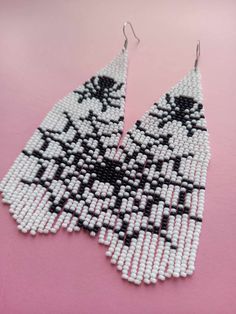 black and white beaded earrings on a pink surface with one earring dangling from the back