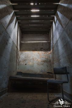 an empty room with a bench in the middle and light coming from above at the end