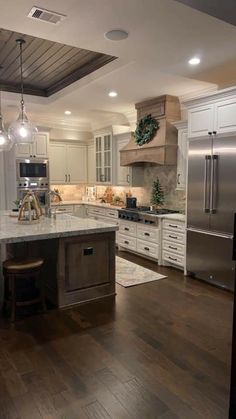 a large kitchen with white cabinets and wood flooring is pictured in this image, there are lights hanging from the ceiling