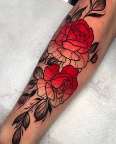 a woman's leg with red roses and leaves on the side of her arm