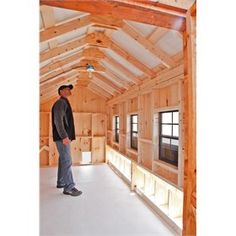 a man standing in the middle of a room with wooden walls and beams on it