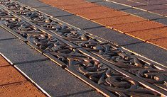 an iron grate on the side of a red brick building with trees in the background