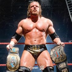 a man in wrestling gear standing next to a rope with his hands on his hips