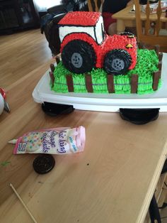 a cake shaped like a tractor on top of a table next to a candy bar