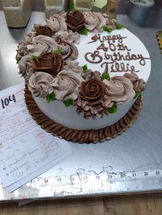 a birthday cake with chocolate frosting and roses on it is sitting on a table