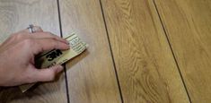 a person is holding a piece of paper on the floor with woodgrains in the background