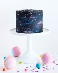 there is a black cake with stars on it and pink balls around the cake stand