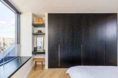 a bedroom with black and white walls, wooden flooring and built - in shelving