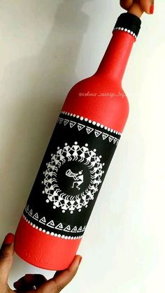 a hand holding a wine bottle that is decorated with black and white designs on it