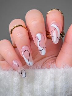 a woman's hand with pink and white nail designs on her nails, holding two gold rings