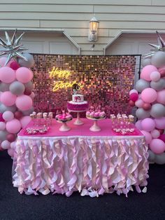 a table topped with pink and silver balloons next to a cake on top of a plate