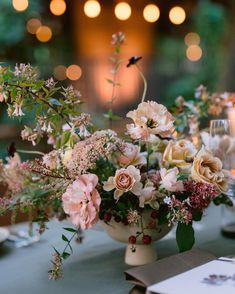 a vase filled with lots of flowers sitting on top of a table covered in candles