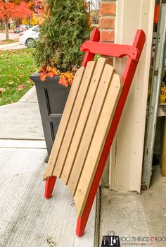 a wooden sled sitting on the side of a building next to a potted plant