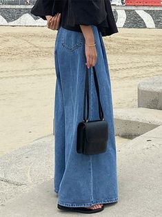 a woman standing on the sidewalk with her hand in her pocket and holding a black purse