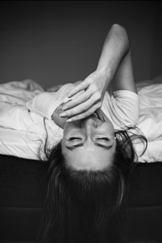 a woman laying on top of a bed with her head in the air