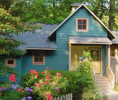 a blue house surrounded by flowers and trees