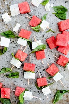 watermelon skewers and basil leaves on a baking sheet