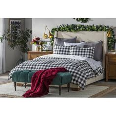 a bed with plaid sheets and pillows on top of it next to a wooden dresser