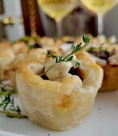 small appetizers on a plate with wine glasses in the background