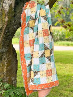 an orange and blue quilt hanging from a tree