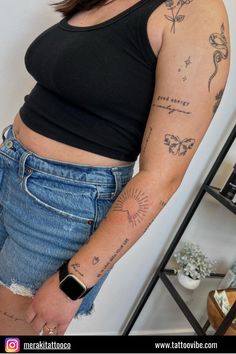 a woman with tattoos on her arm standing next to a wall