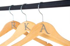 two wooden clothes hangers with the letters k and a on them hanging from a black rail