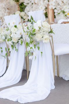 the chairs are decorated with white flowers and greenery for an elegant wedding or special event