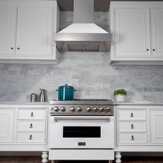 a stove top oven sitting inside of a kitchen next to white cupboards and drawers