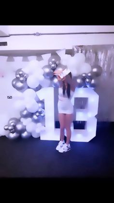 a girl is standing in front of balloons and the numbers are white with silver trim