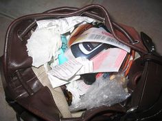 a brown bag filled with toilet paper and other items sitting on the floor next to a purse