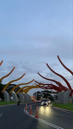 an art installation on the side of a road with cars driving down it at dusk