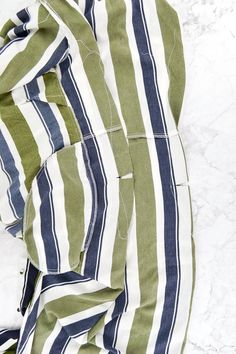 an unbuttoned green and white striped shirt laying on top of a marble floor