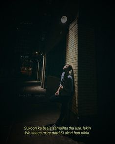 a man sitting against a brick wall in the dark