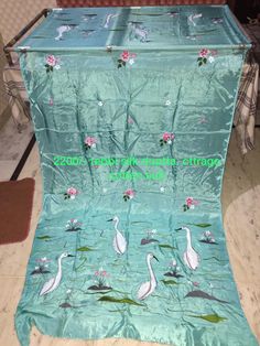 a blue blanket with white birds and flowers on it in the middle of a room